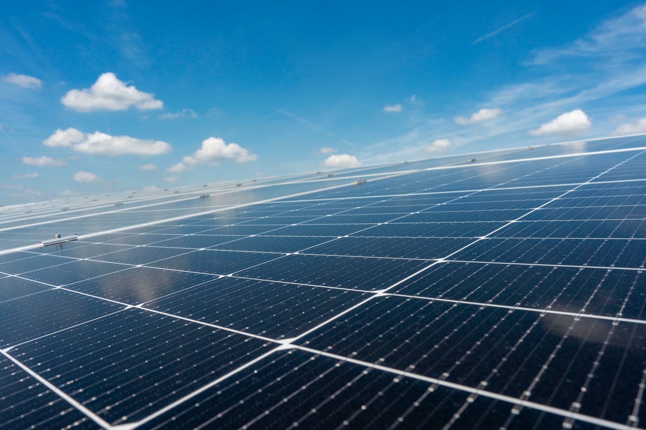 A solar panel field displaying dark solar panels under a clear blue sky.