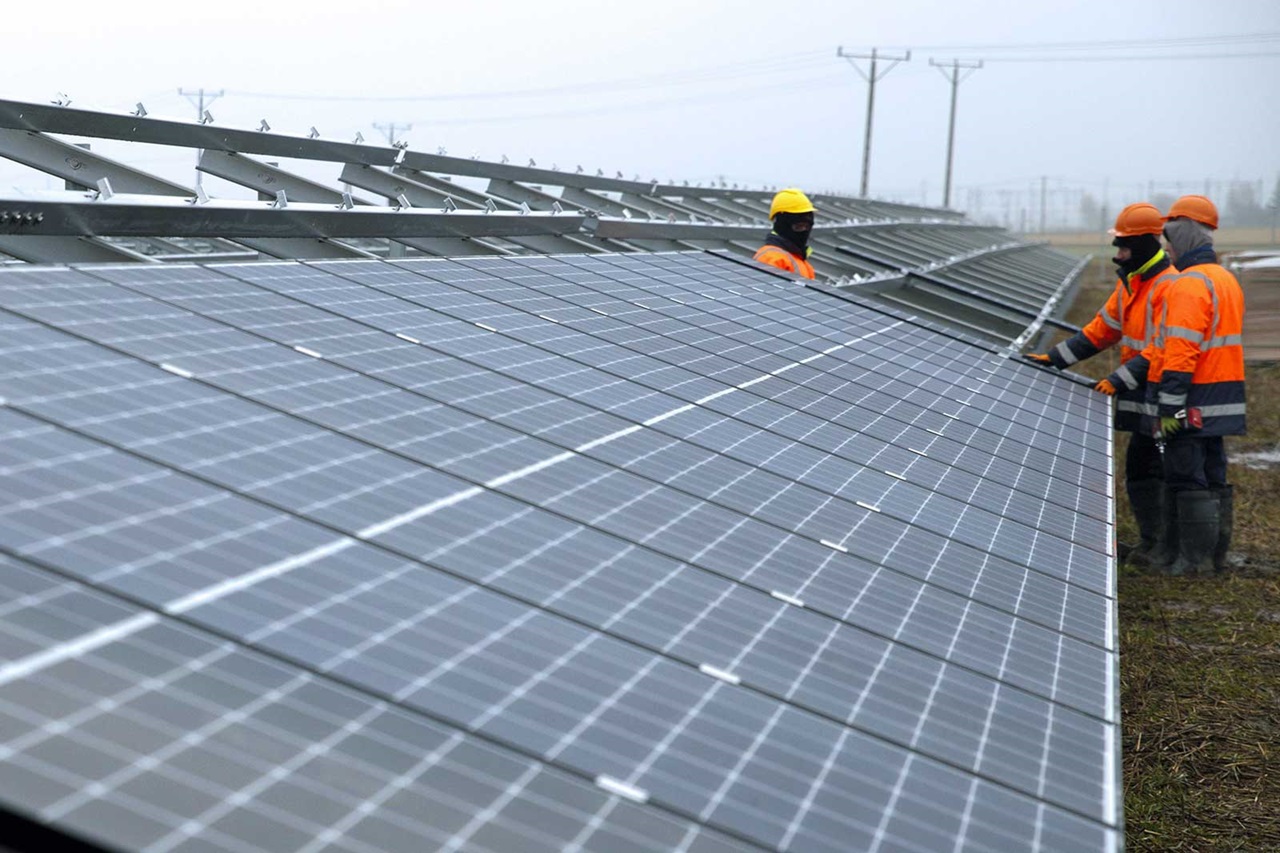 Workers install solar panels in a field, contributing to sustainable energy production.